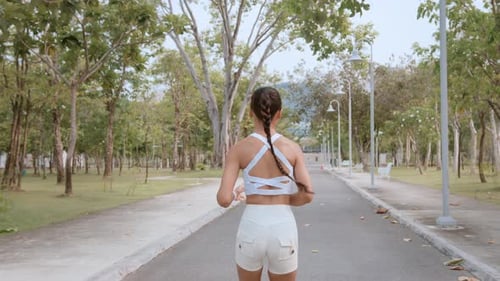 Young fitness woman in sportswear jogging in city park