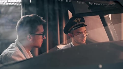pilots in the cockpit of the plane near the control panel with a tablet in their hands discuss