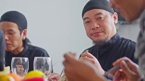 Close-up of middle-aged Asian Muslim man enjoying festive meal with family during eid celebrations