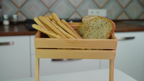 Homemade Cheese Bread Sticks and Fresh Toaster Bread Rotate in a Light Wooden Basket