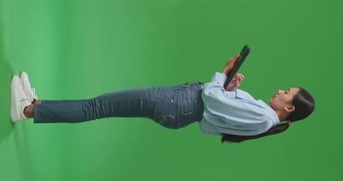 Full Body Asian Woman Using Tablet An Looking Around On Green Screen Background In The Studio