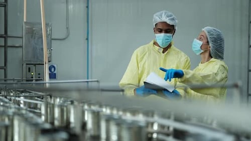 Deux superviseurs industriels examinent le contrôle de la qualité de la production d'aliments en conserve.