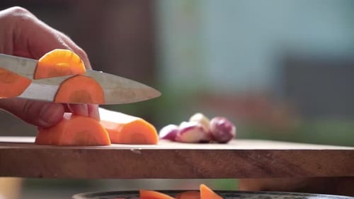 Cutting Fresh Carrots with Knife on Cutting Board