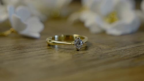 A close-up of a beautiful engagement ring lying on a table with a floral background