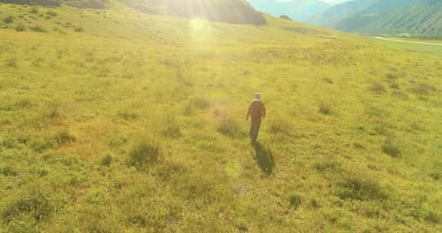 Flight Over Backpack Hiking Tourist Walking Across Green Mountain Field Huge Rural Valley at Summer