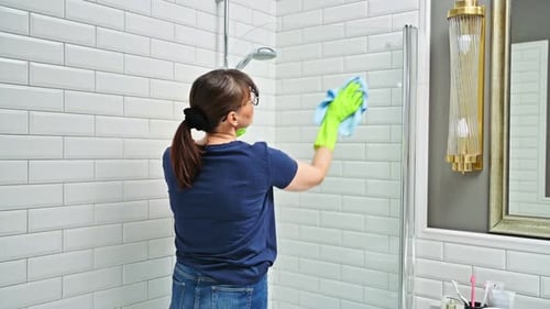 Woman Cleaning Bathroom Washing Glass in Shower