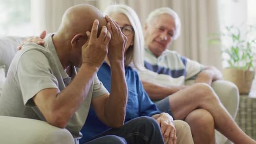 Senior Adults Comforting a Distraught Friend on Sofa