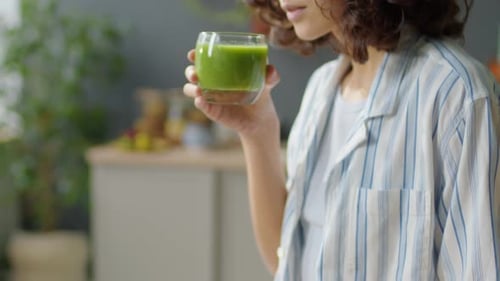 Young Woman Drinking Green Smoothie at Home