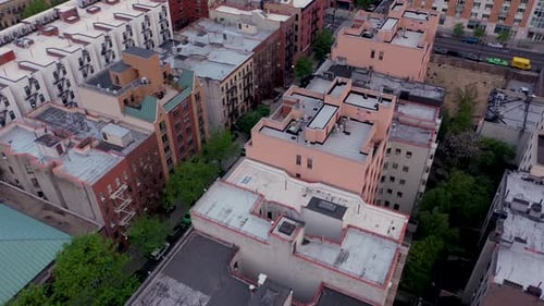slow smooth aerial footage over Harlem NYC showing rooftops, empty streets, and a trash strewn lot.