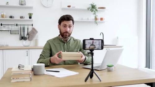 Man Unboxing Product While Filming in Kitchen