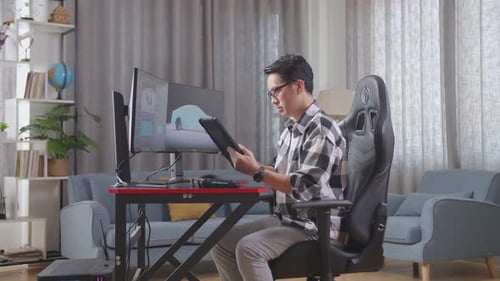 Man Working on Tablet and Computer at Home