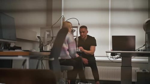 in an Ophthalmology Clinic Young Doctor Tells How Diagnostics are Carried Out to a Young Girl