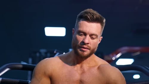 Athlete with strong body posing on gym background. Perfect man`s body. Slow motion.