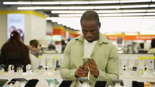 Customer Comparing Smartphones in Electronics Store