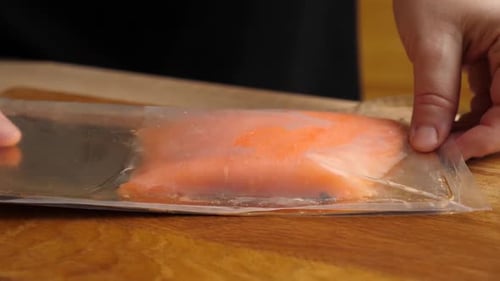Opening Package of Sliced Salmon on Wood