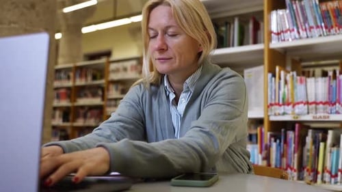 Mature College Student Working On Project Elderly Woman Using Laptop at University Library Education