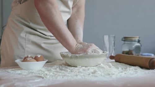 The cook in the bakery kneads the dough with his hands and begins to prepare bread.