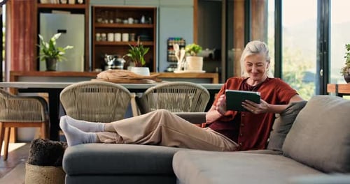 Senior Woman Relaxing on Couch Using Tablet