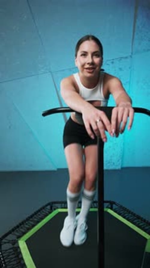 Woman Bouncing on a Rebounder Trampoline Indoors