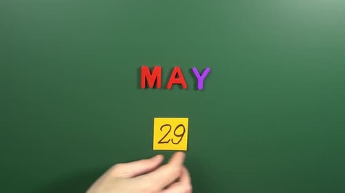 Hand sticking a sticker 29 May calendar day on school board. 29 date of May. Twenty ninth day