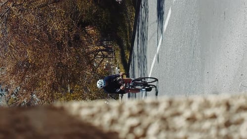 Vertical shot professional cyclist riding a bike on asphalt road