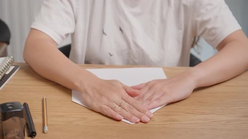 Woman Folding White Paper on Wooden Desk