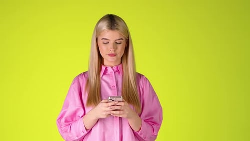 Blonde Woman Holding a Smartphone Texting and Smiling, Studio Shot