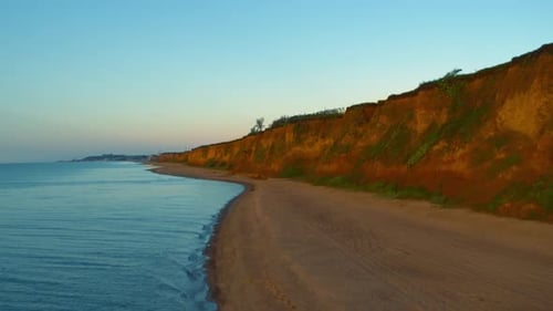 Aerial rocky beach view with charming cloudless sky. Waves splashing on beach.