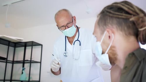 Doctor giving injection to young adult male patient