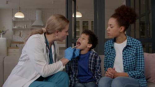 Female ENT Doctor Doing Medical Checkup of Ill Child Sore Throat at Home