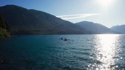 Two kayaks paddled on wavy lake water by Andes mountains, static view
