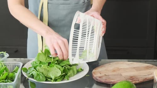 The girl puts greens on a wooden board, prepares dinner. Low calorie, diet, healthy eating