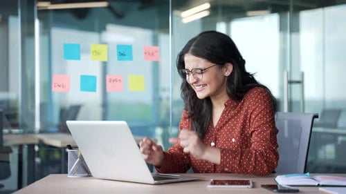Excited Woman Celebrating Success at Modern Office Desk