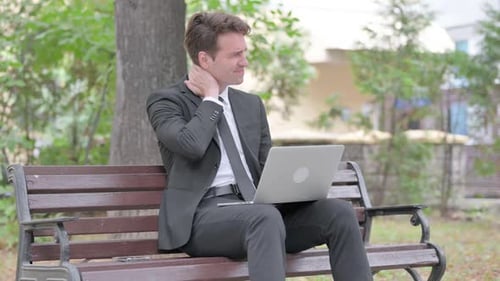 Man with Neck Pain Working on Laptop in Park