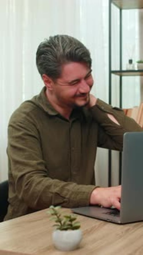 Man Massages Stiff Neck While Using Laptop