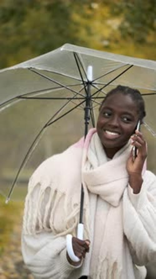 Smiling Woman Talking on Phone in Park with Umbrella