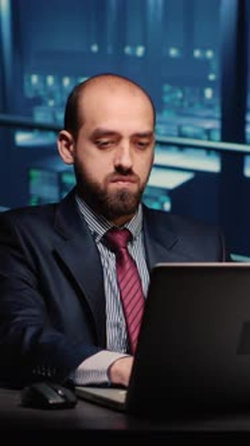 Man Works at Laptop in Dimly Lit Office