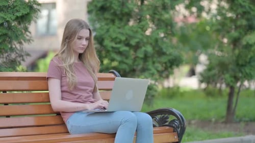 Woman Typing on Laptop in Urban Park