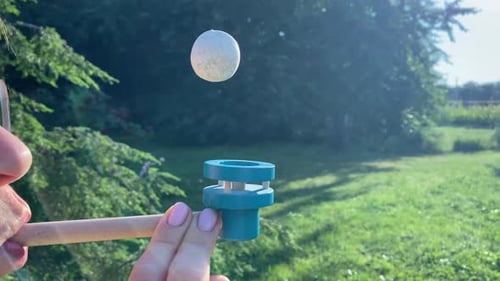 Woman balancing ball of blow pipe toy as analogy of balance life