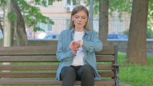 Waiting Young Woman Checking Time while Sitting on Bench in Park