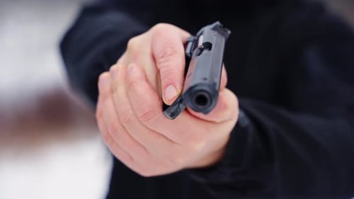Close up of man's hand holding pointing a gun
