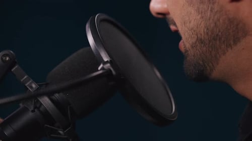 Closeup Portrait of Bearded Man in Glasses Talks in Mic with Diaphragm in Studio