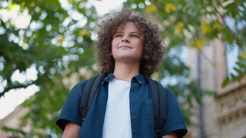 Bottom Angle View Portrait of Smiling Schoolboy Looking Away Talking in Slow Motion and Looking at