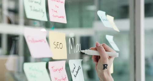 Woman Writing Marketing Terms on Glass Board