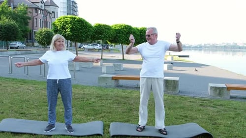 Portrait of a Smiling Elderly Couple Exercising in a City Park