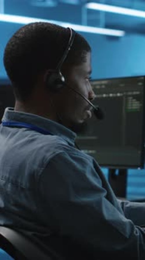 Vertical Video Man Using Headphones Mic to Talk with Manager Supervising Data Center