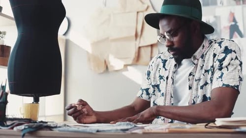 Creative Man Designing Clothes in Studio Workspace