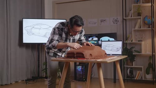 Man Designer Using Rake To Smooth Out The Surface And Create Details In The Sculpture Of Car Clay