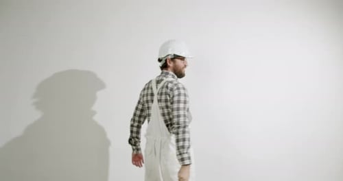 Mann malt eine weiße Wand mit einem Farbroller
