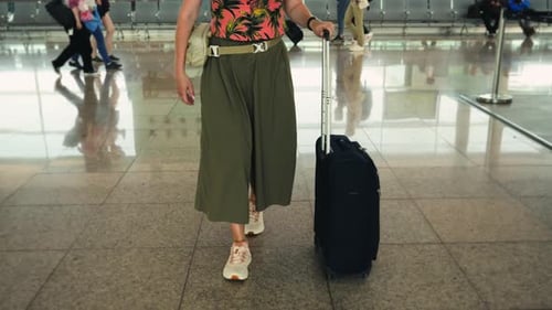 Rear View of Woman Traveler Walking with Suitcase at the Modern Airport Terminal Ready for Vacation